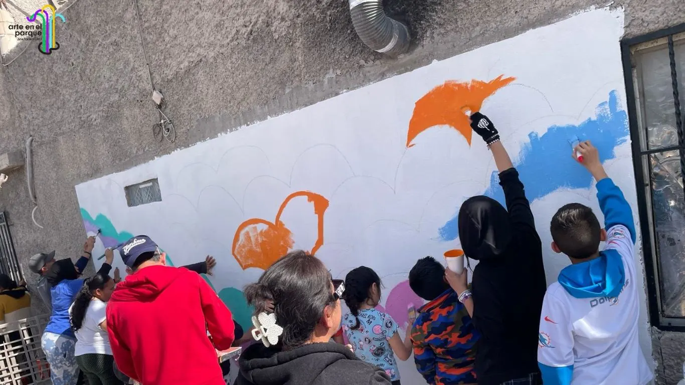 Niñas y niños pintan juntos un mural en una pared