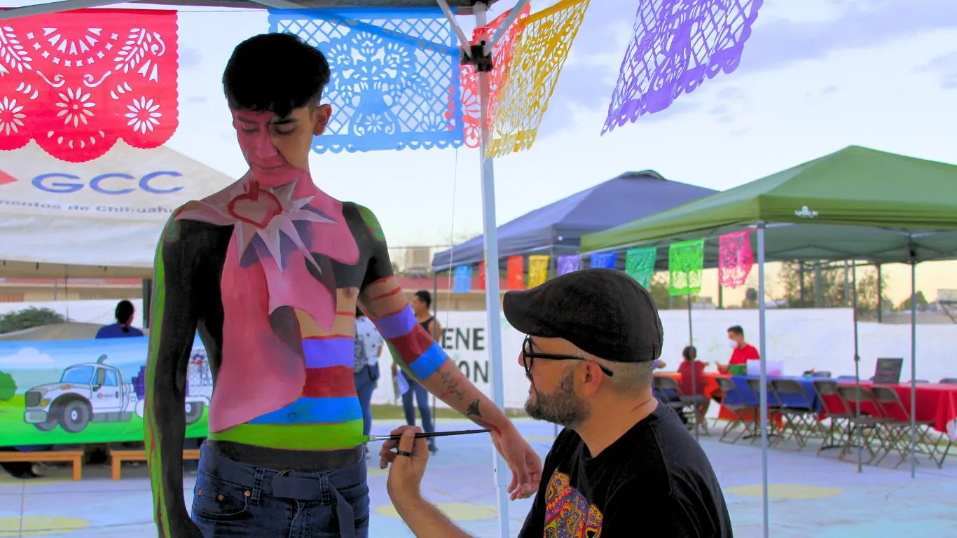 Pintura corporal en un evento bajo papel picado